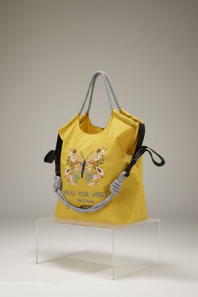 Product shot of Ball&Chain yellow nylon handbag, highlighting its embroidered butterfly design and functionality.