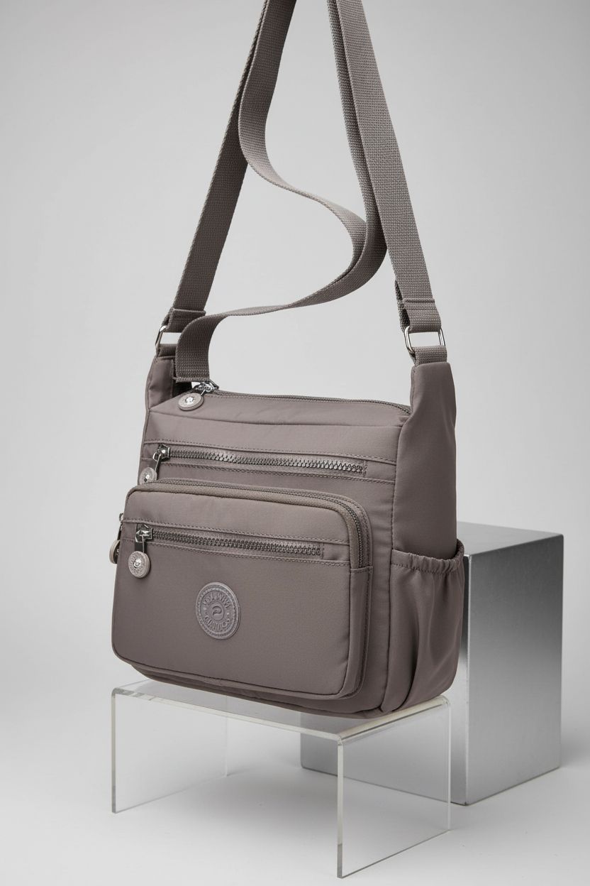 Pealwel grey handbag on acrylic riser, highlighting multiple pockets and zip features in detail.