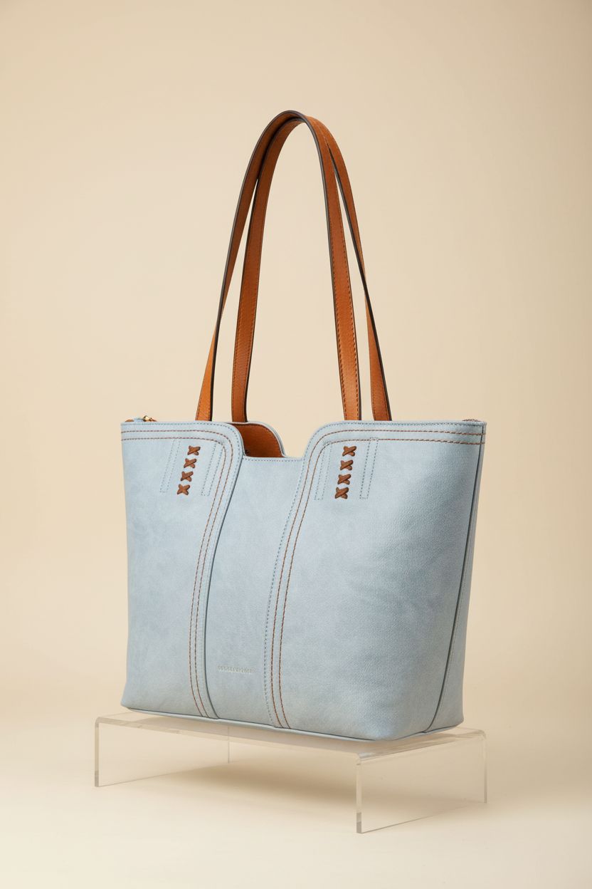 Montana West powder-blue tote bag displayed on a clear acrylic riser, highlighting its stylish design and quality materials.