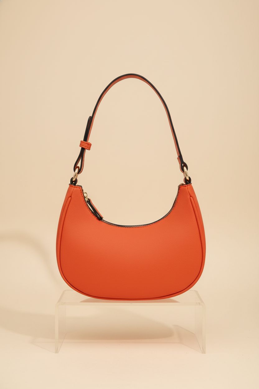 FashionPuzzle burnt orange crescent bag showcased on a minimalist studio backdrop