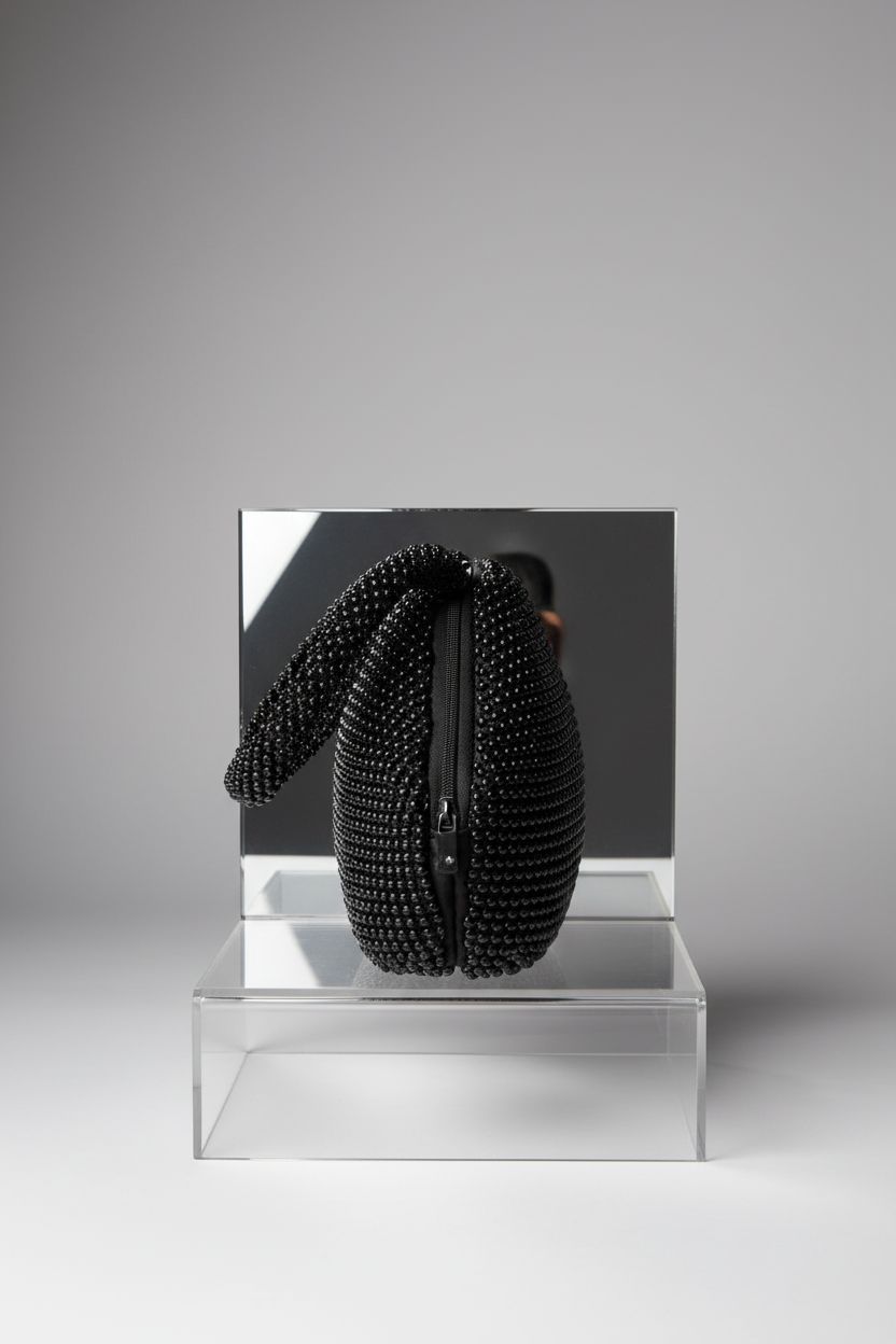 Detailed view of BABEYOND black beaded triangle clutch on acrylic riser