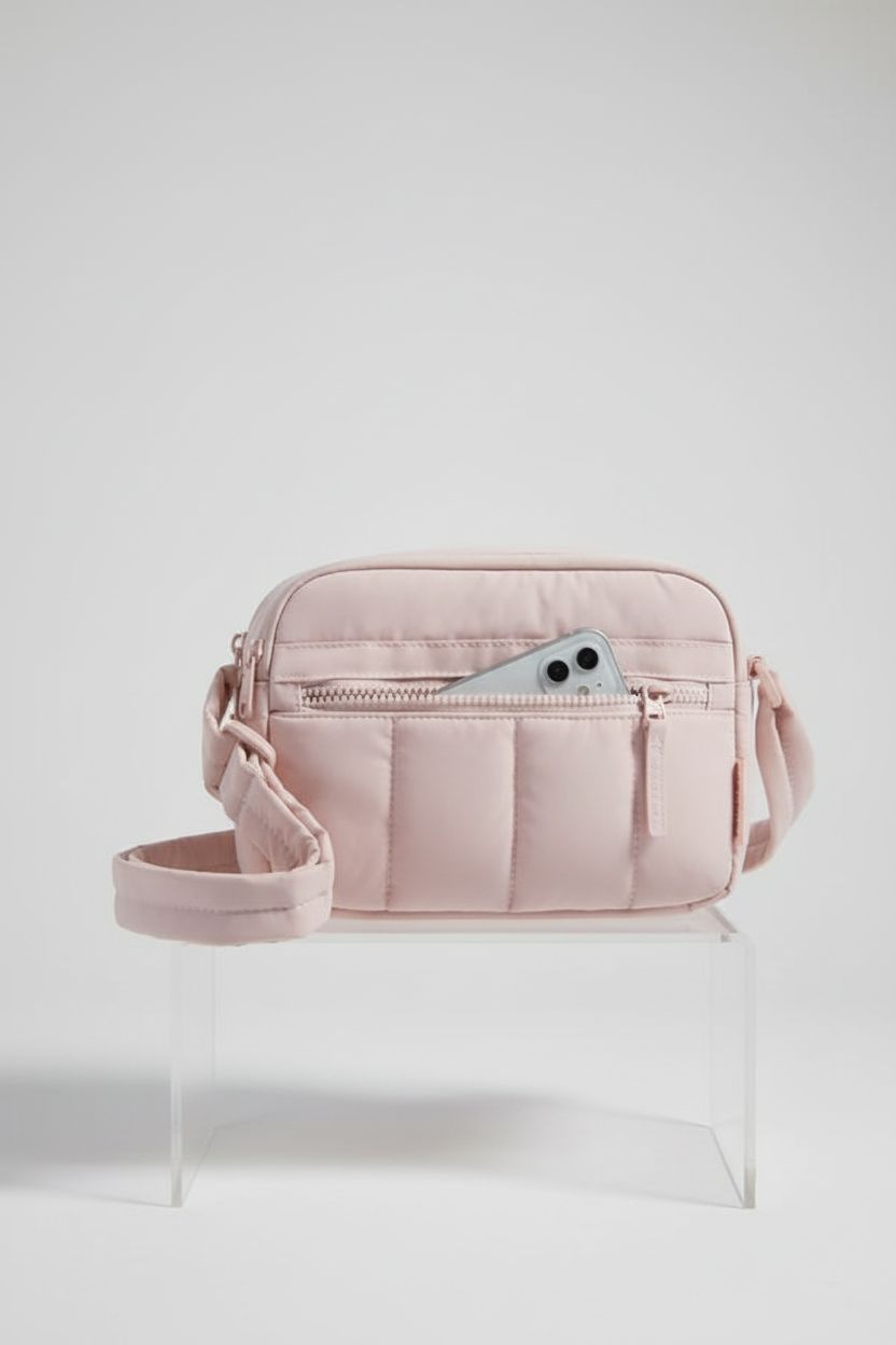 BAGSMART baby pink crossbody bag displayed on a clear riser, showcasing its quality craftsmanship.