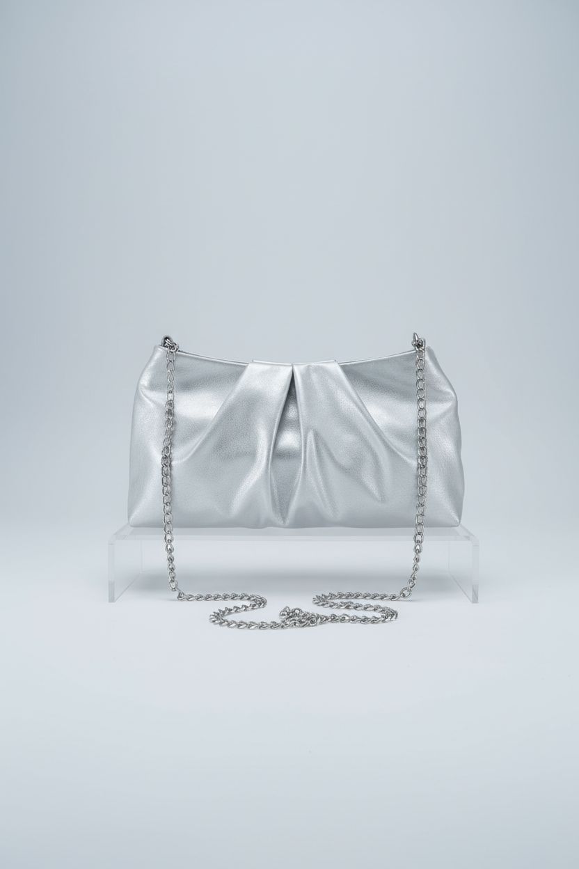 FLAIRFOLIO silver evening bag featured on a minimalist acrylic riser against a gray backdrop.