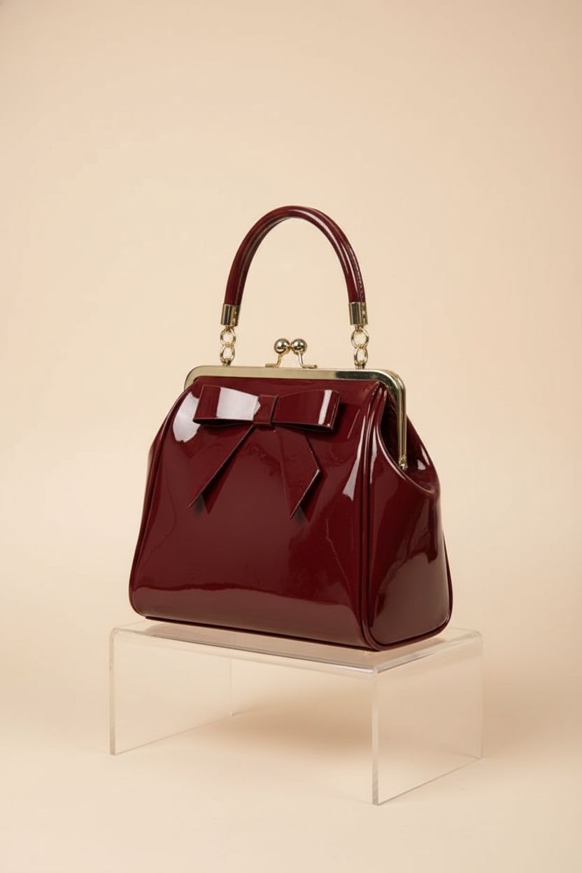 Dancing Days burgundy patent top-handle bag elegantly presented on a seamless backdrop for a chic product shot.